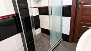 a glass shower in a bathroom with black and white tiles at For rest Hostel in Lublin +57 photos