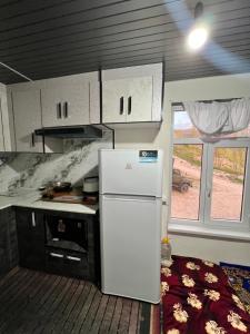 a kitchen with a white refrigerator and a stove at Shahzod Guesthouse & Homestay in Gelen