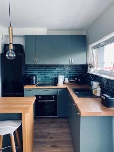 a kitchen with blue cabinets and a wooden table at Apartament u Liska in Rumia