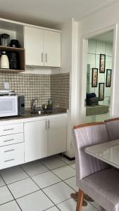 a kitchen with white cabinets and a microwave at Flat Gran Solare Lençóis Barreirinhas in Barreirinhas