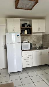 a kitchen with a white refrigerator and a microwave at Flat Gran Solare Lençóis Barreirinhas in Barreirinhas