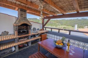 a balcony with a table and an outdoor oven at Agapito's Houses in Praia de Odeceixe