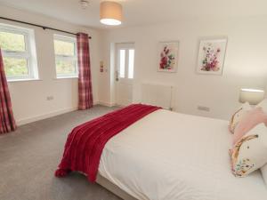 a bedroom with a white bed and two windows at Little Plumtree in Milnthorpe