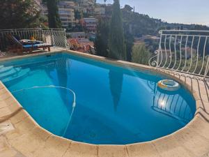 a large blue swimming pool with a view of a city at Studio with private pool in Villefranche-sur-Mer