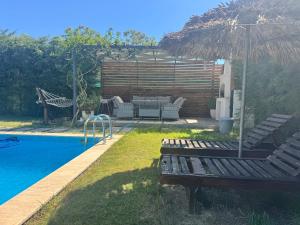 a backyard with a pool with a bench and an umbrella at Villa Rüzgar in Dalaman