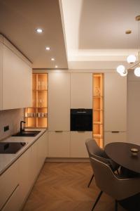 a kitchen with white cabinets and a table with chairs at Designer Suite • Pool & Sauna • Pipera Metro in Bucharest