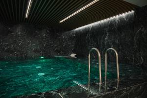 a swimming pool with green water in a dark room at Designer Suite • Pool & Sauna • Pipera Metro in Bucharest