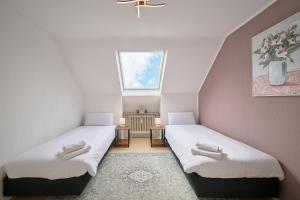 two beds in a small room with a window at SANO - Hagen - Hegel in Hagen