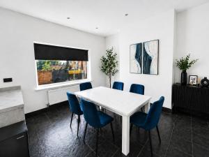 a dining room with a white table and blue chairs at The Carlton Collection in Birkenhead