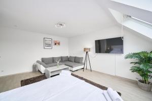 a white living room with a couch and a tv at SANO - Hagen - Hegel in Hagen