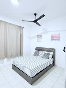 a white bedroom with a bed and a ceiling fan at Nj Guesthouse in Tawau