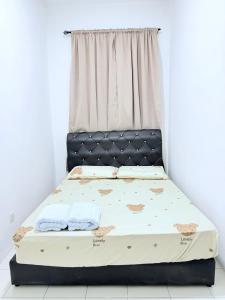 a bed with two towels on it in front of a window at Nj Guesthouse in Tawau