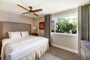a bedroom with a bed with a ceiling fan and a window at Inviting Ocean View Condo Pono Kai Resort G104 in Kapaa