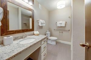 a bathroom with a sink and a toilet and a mirror at Inviting Ocean View Condo Pono Kai Resort G104 in Kapaa