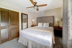 a bedroom with a large white bed with a ceiling fan at Inviting Ocean View Condo Pono Kai Resort G104 in Kapaa