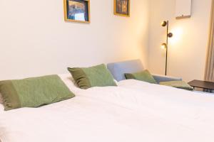 a white bed with two green pillows and a chair at Hyggehuus Tossens - Küste33 41 in Tossens +33 photos