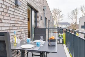 a balcony with a table with plates and wine glasses at Hyggehuus Tossens - Küste33 41 in Tossens