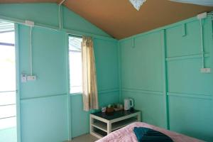 a bedroom with blue walls and a bed and a window at Phi Phi Oceanview Hill Bungalows in Phi Phi Islands