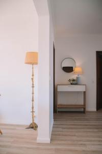 a white room with a floor lamp and a mirror at Just Like Home - Retorta do Pico in Caminha