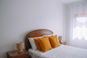 a bedroom with a bed with yellow pillows and a window at Just Like Home - Retorta do Pico in Caminha
