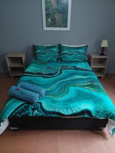 a bed with a blue comforter on it at Cozy Corner Serenity Suite in Bredasdorp