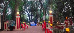a patio with red chairs and lights in a park at The Wayside Inn in Matheran
