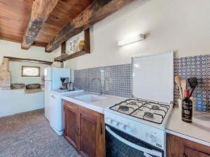 a kitchen with a white stove and a sink at Holiday Home Le Petit Gîte by Interhome in Jayac