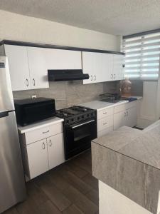 a kitchen with white cabinets and a black stove at Departamento con ubicacion priviligiada cerca de la playa in Acapulco