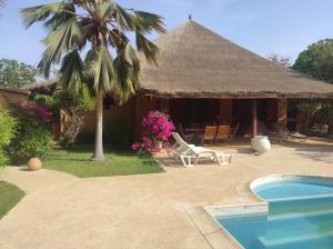 a resort with a pool and a hut with a palm tree at Superbe villa avec piscine privée à 500m de la plage à Nianing in Nianing