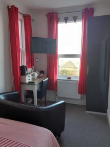 a hotel room with a desk and red curtains at South Beach B & B in Lowestoft