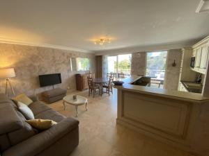 a living room with a couch and a kitchen and a table at Apartment Le Domaine de la Baie-1 by Interhome in Cavalaire-sur-Mer