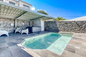 a swimming pool with chairs and a stone wall at Villa Ô Ti Paille-en-queue - 14 voyageurs in Saint-Joseph