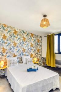 a bedroom with a large white bed with a tropical wallpaper at Villa Ô Ti Paille-en-queue - 14 voyageurs in Saint-Joseph +49 photos