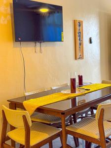 a dining room table with chairs and a television on the wall at Residential Jula in Los Prados