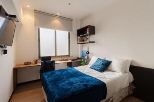 a bedroom with a bed and a desk and a window at Uliving Rio in Rio de Janeiro