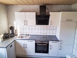 a kitchen with white cabinets and a stove top oven at Apartment Orpington by Interhome in Dreisbach