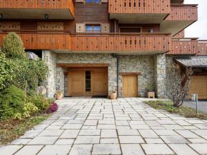a large house with wooden doors and a patio at Apartment Pré Vert 3 by Interhome in Villars-sur-Ollon