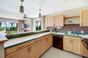a large kitchen with wooden cabinets and a sink at Ocean View Condo Pono Kai Resort PF-G102 in Kapaa