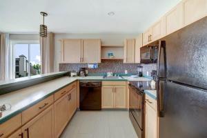a kitchen with wooden cabinets and a stainless steel refrigerator at Ocean View Condo Pono Kai Resort PF-G102 in Kapaa