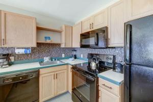 a kitchen with wooden cabinets and a black refrigerator at Ocean View Condo Pono Kai Resort PF-G102 in Kapaa +37 photos