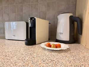 a plate of fruit on a counter next to a coffee maker at Kossuth Vendégház in Tolna