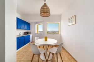 a kitchen with blue cabinets and a white table and chairs at Sunny Beach Praia da Rocha Sea Views Algarve in Portimão