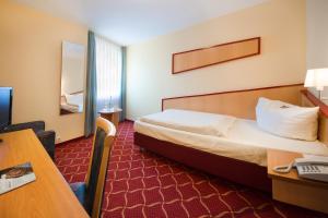 una camera d'albergo con letto e scrivania di Montana Hotel a Oberasbach