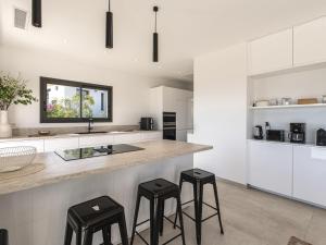 a kitchen with white cabinets and black stools at Villa Casa Minà by Interhome in Sari Solenzara +26 photos