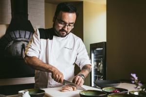 a man in a kitchen preparing food on a cutting board at Octant Furnas in Furnas