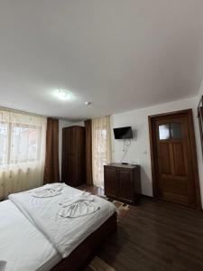 a bedroom with a large bed and a television at Pensiunea Valea Galbenei in Arieşeni