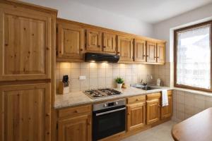a kitchen with wooden cabinets and a stove top oven at Appartamento Alta Valle Maira - Nebin in Villaro