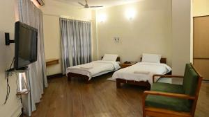 a room with two beds and a flat screen tv at Aijal Club in Āīzawl