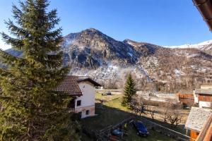 a house with a tree in front of a mountain at Appartamento Alta Valle Maira - Nebin in Villaro +2 photos