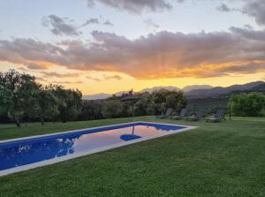 a pool in the grass with a sunset in the background at La Masoveria de Mateus in Sagás